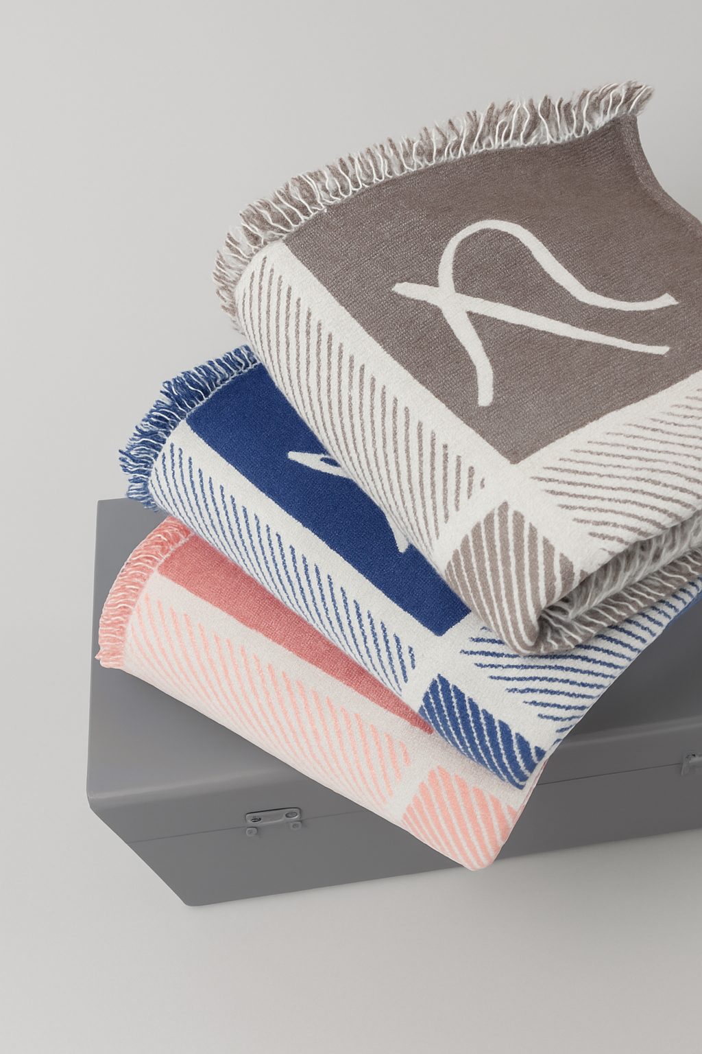 Stack of patterned blankets on a gray surface with a light gray background